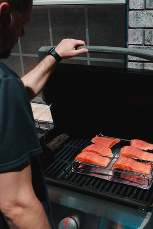close up of man putting fresh salmon steaks on a grill