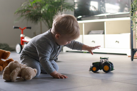 little boy playing with toy car in living room, blurred background