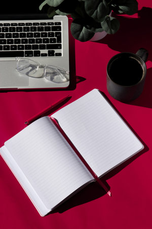 flat lay composition of empty notebook, coffee, computer and glasses on magenta backgroundの写真素材