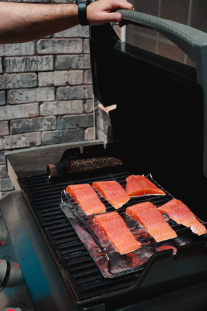 close up of man putting fresh salmon steaks on a grillの写真素材