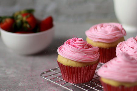 close up of vanilla muffins decorated with pink buttercream frosting on topの写真素材