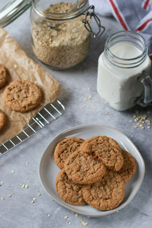 fresh baked oatmeal cookies on baking rack, milk and oats in background