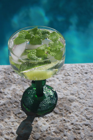 close up of a cold mojito cocktail with limes at the pool
