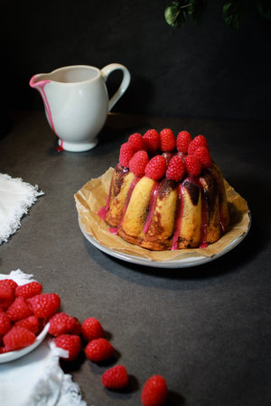 home made marble cake with sugar glaze and raspberries on top, dark grey backgroundの写真素材