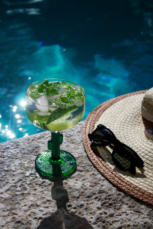 cold mojito cocktail with limes at the pool with black sunglasses and straw hatの写真素材