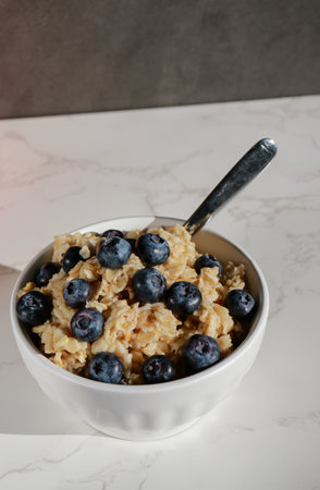 healthy vegan oatmeal with blueberries in white porcelain bowlの写真素材