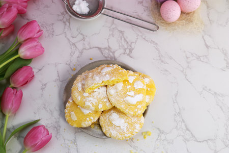 top view of lemon cracked cookies on plate, easter. theme with eggs and tulipsの写真素材