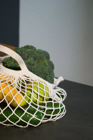 close up of an eco mesh bag full with fresh vegetables on grey marble tableの写真素材