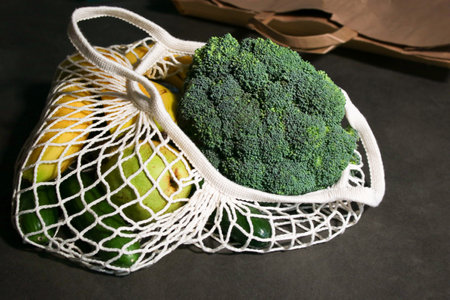 close up of an eco mesh bag full with fresh vegetables on grey marble tableの写真素材