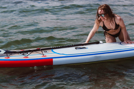 Young woman pushing a sup board in the sea. Healthy and fit life in the nature.の写真素材