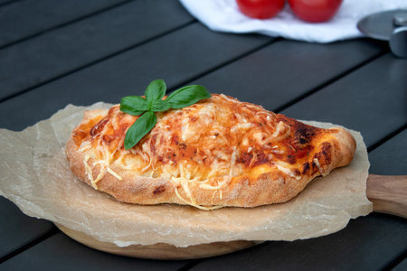 Close up of pizza calzone with tomato sauce pesto and cheese on wooden plateの写真素材