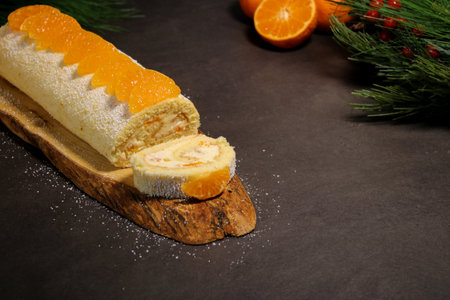 Delicious tangerine cake roll with vanilla buttercream filling on wooden plate, holiday winter dessertの写真素材