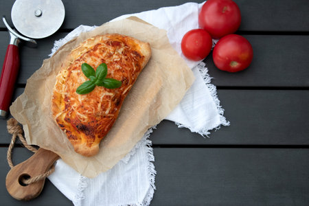 Home made pizza calzone with tomato sauce pesto and cheese on wooden plate
