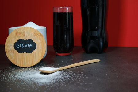 A glass of a drink and natural sweetener with a spoon, red background