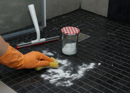 Close up of womans hands in orange gloves cleaning shower floor with baking soda, eco friendly cleaningの写真素材