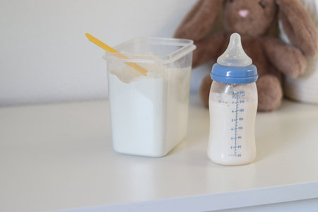 Close up of a feeding bottle with baby formula milk on white tableの写真素材