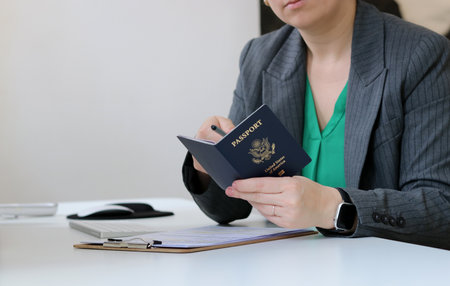 Close up of a caucasian woman holding an American passport at office tableの写真素材
