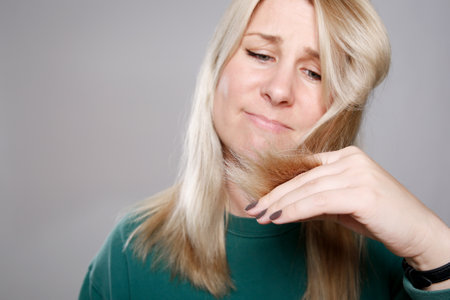 Close up woman checking and worrying about her split ends. Blond damaged hair conceptの写真素材