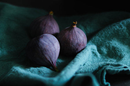 Close up of fresh ripe fig fruits in green fabric with dark shadowsの写真素材
