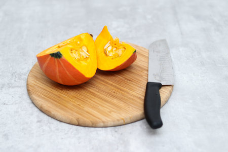 Fresh half sliced Hokkaido pumpkin on a wooden board with a knifeの写真素材