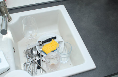 White ceramic kitchen sink full with dirty unwashed dishesの写真素材