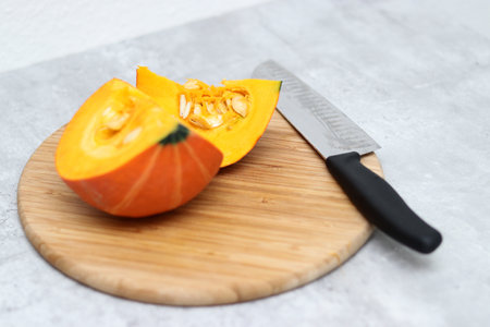 Fresh half sliced Hokkaido pumpkin on a wooden board with a knifeの写真素材