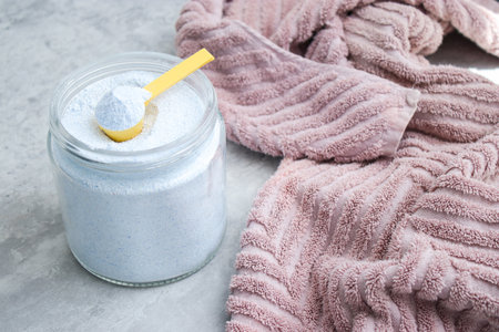Close up of washing powder and a dirty towel on grey table. Cloth stain remover conceptの写真素材