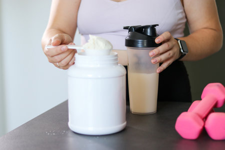 Close up of woman preparing a protein shake in the kitchen. Diet meal replacement for weight lossの写真素材