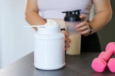 Close up of woman preparing a protein shake in the kitchen. Diet meal replacement for weight loss