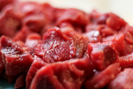 Close up of red raw beef meat chopped in small cubes on cutting board