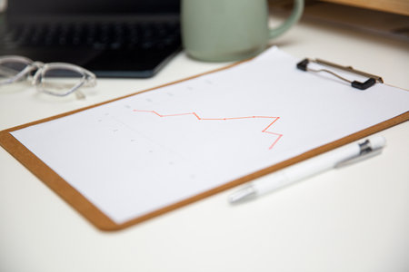Office workplace table with charts report on wooden clipboard, coffee, supplies and laptop.の写真素材