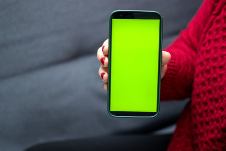 Close up of a woman holding a smartphone wit a green screen
