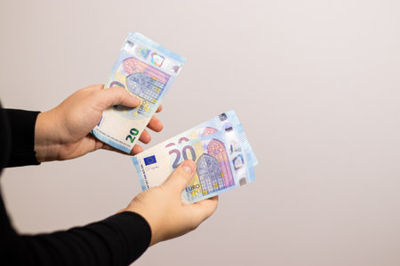 Close up of a woman counting twenty euro bills, grey backgroundの写真素材