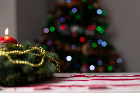 Close up of an advent wreath on the table with one red burning candle, blurry bokeh background with lightsの写真素材