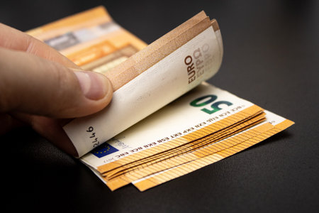 Close up of a woman counting fifty euro bills on dark table background