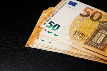 Close up of fifty euro money bills on black background