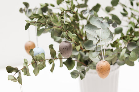 Colorful easter eggs hanging decorative on eucalyptus plant in a vaseの写真素材
