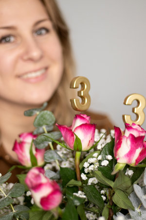 Close up of birthday candles on flowers, blurry background with a happy womanの写真素材