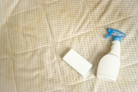 A spray bottle with a sponge on a mattress. Cleaning textile at home conceptの写真素材