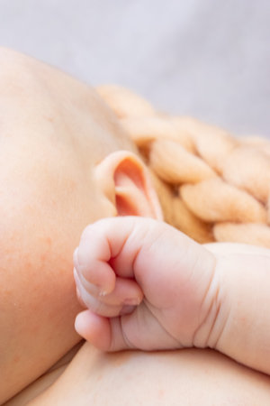 Close up of a newborn babys tiny hand and head, sleeping in a cozy bed