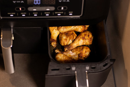 Close up an open air fryer with roasted chicken drumsticks insideの写真素材