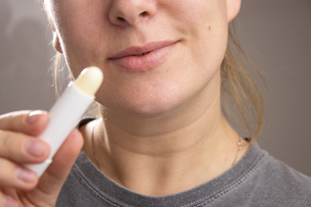 Close up of a caucasian woman holding a hygienic lip balm stick for lipsの写真素材