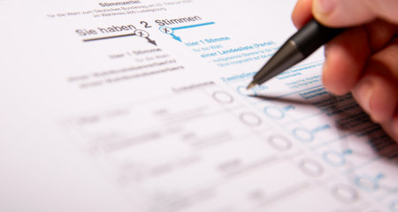 12. February 2025 - Berlin, Germany. Close up of a female hand marking CDU party on a ballot paper...