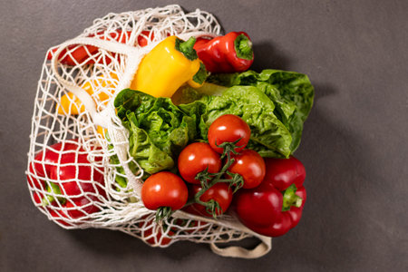 Close up of fresh seasonal vegetables in an eco net shopper bag on grey kitchen tableの写真素材