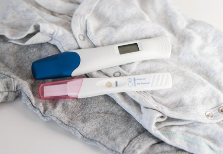 Close up of two positive pregnancy tests on baby clothesの写真素材