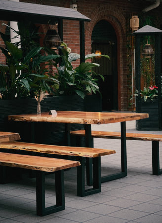Restaurant interior with wooden table and wooden benches, green palm trees as decorationの写真素材