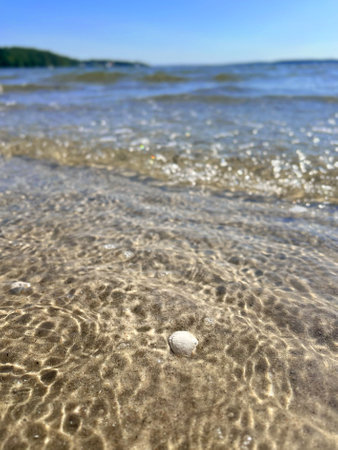 Close up of beach sand and ocean water, blue sky in backgroundの写真素材