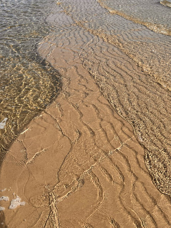 Close up of textuted beach sand and transparent ocean water