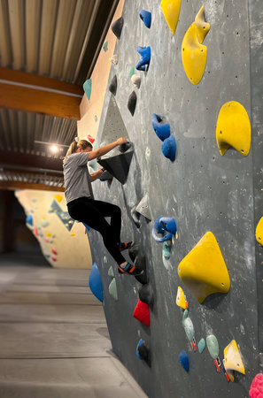 A woman climbing a wall in a indoor bouldering centerの写真素材