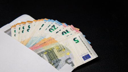 Close up of euro money bills fanned out in a envelope, black backgroundの写真素材